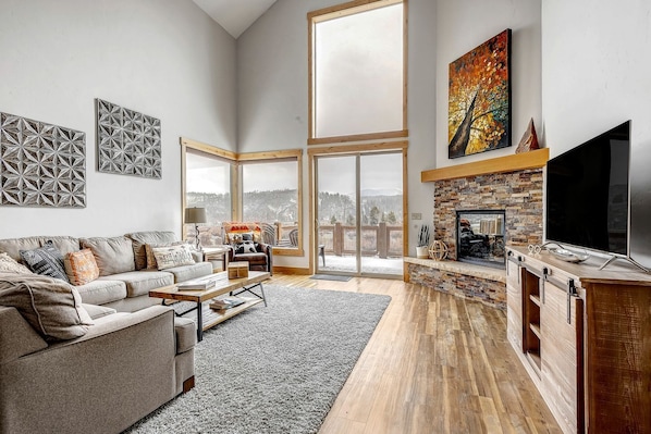 A spacious living room with a fireplace, large windows, and a cozy seating area.