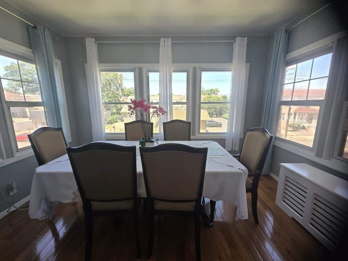 A dining room with a table set for four, large windows, and a view of the outside.