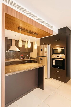 Una cucina moderna con isola centrale, elettrodomestici in acciaio inossidabile, illuminazione a sospensione e soffitto in legno.