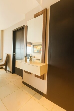 Un bagno moderno con una porta in legno scuro, un mobile lavabo bianco con uno specchio e un pavimento piastrellato.