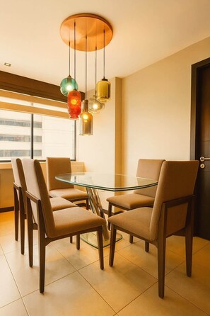 Zona pranzo moderna con tavolo in vetro, sedie in legno e lampade a sospensione.