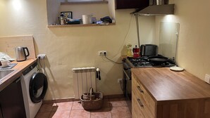 Une cuisine de taille réduite équipée d’un lave-linge, d’une cuisinière, d’un évier et d’une fenêtre située au-dessus de l’évier.