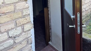 Ein Durchgang zu einer Treppe, eine Tür mit Griff und eine kleine Plakette an der Wand.