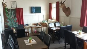Uma sala de jantar com uma mesa, cadeiras, um pinheiro de Natal e um troféu de chifre de veado na parede.