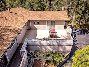 A two-story house with a covered patio, a fenced deck, and a small garden area.
