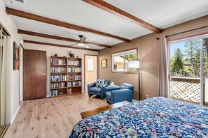 A bedroom with a large bed, a bookshelf, a desk, and a chair.