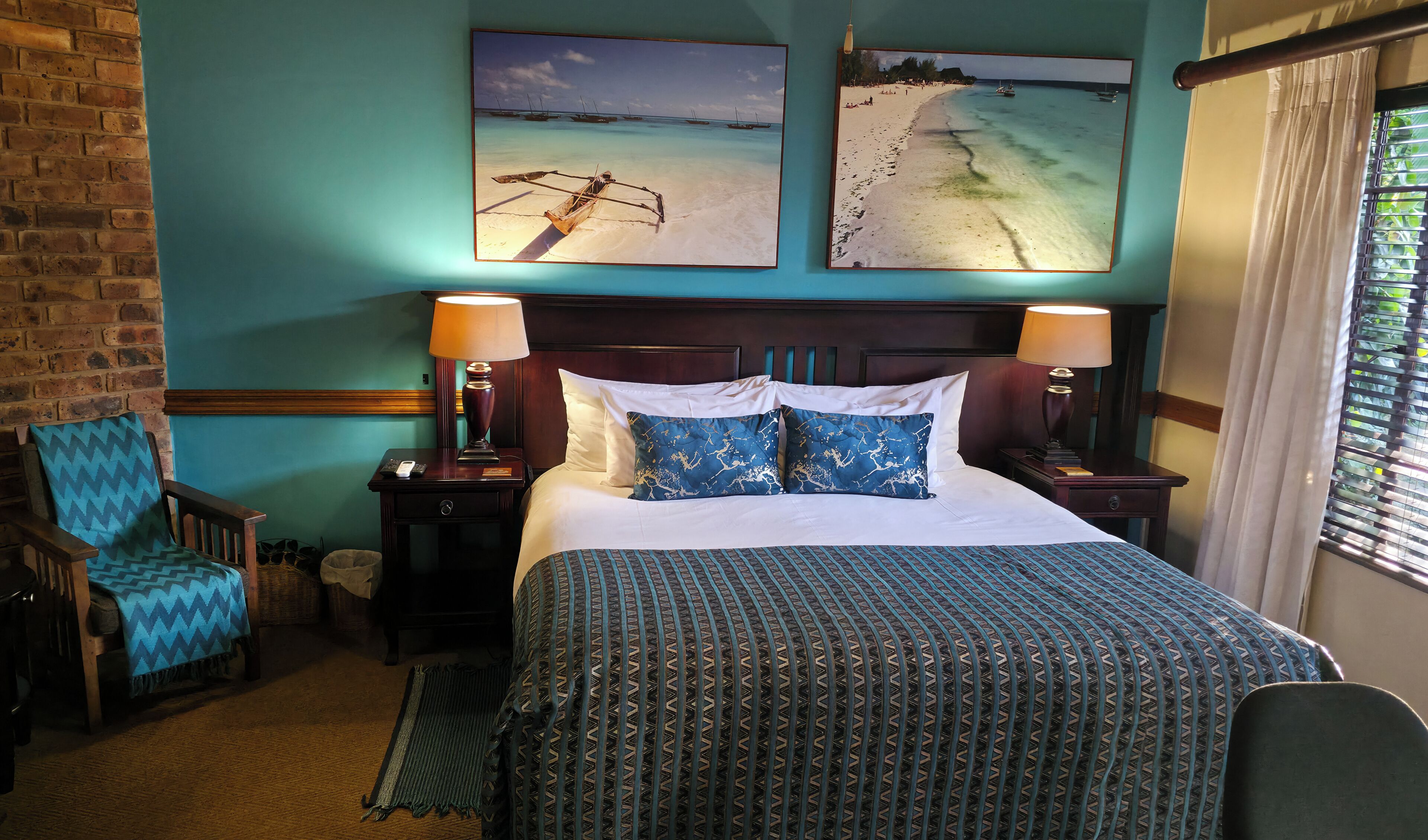 Ein Hotelzimmer mit einem Bett, zwei Nachttischen, einem Sessel und zwei Wandbildern.