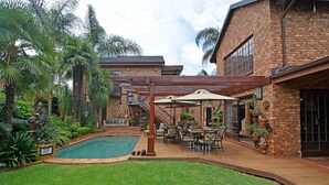 Un patio trasero con piscina, muebles de jardín y una casa de ladrillo.