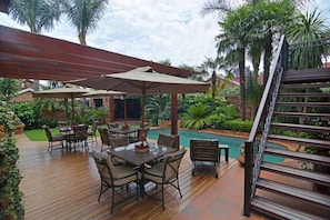Une terrasse en bois avec des meubles d’extérieur, une piscine et un escalier.