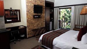 Habitación de hotel con cama, escritorio, silla, televisión y vista al exterior.