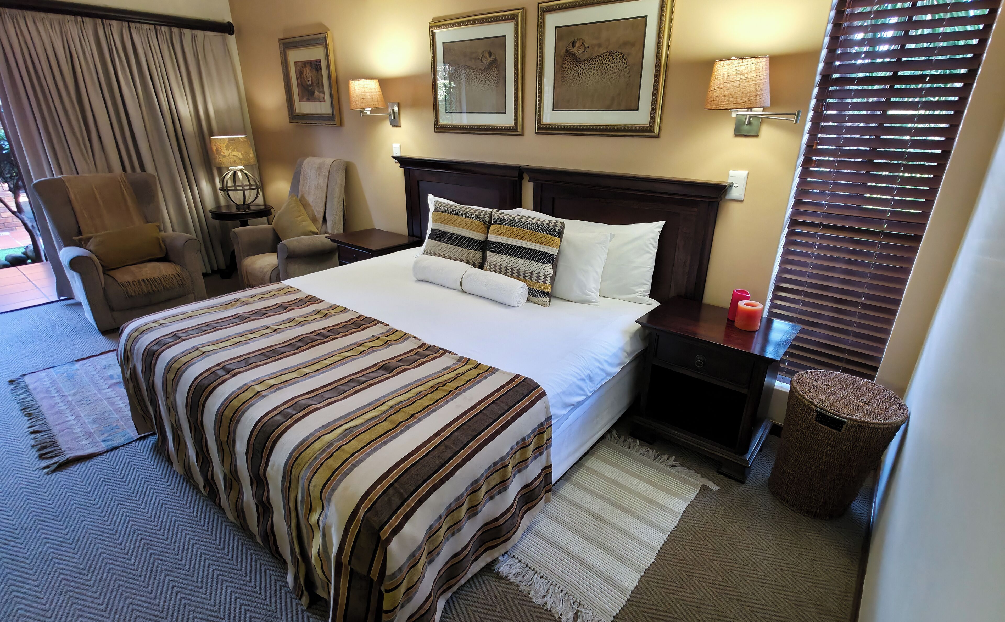 Habitación de hotel con cama, una silla, mesita de noche, lámpara y un cuadro en la pared.