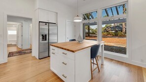 A modern kitchen with a wooden countertop, white cabinetry, and a built-in refrigerator.