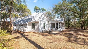 A white house with a porch, surrounded by trees.
