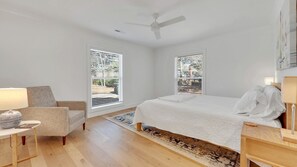 A bedroom with a bed, a chair, a desk, and a ceiling fan.