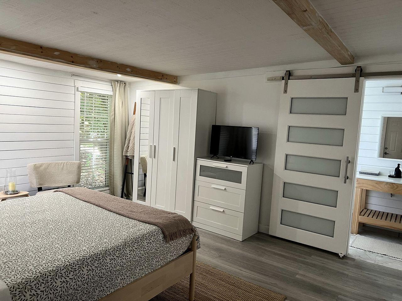 A bedroom with a bed, a TV, a wardrobe, and a sliding door.