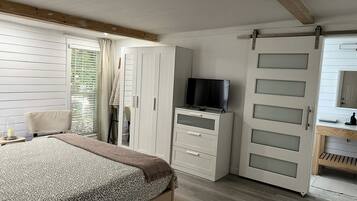 A bedroom with a bed, a TV, a wardrobe, and a sliding door.