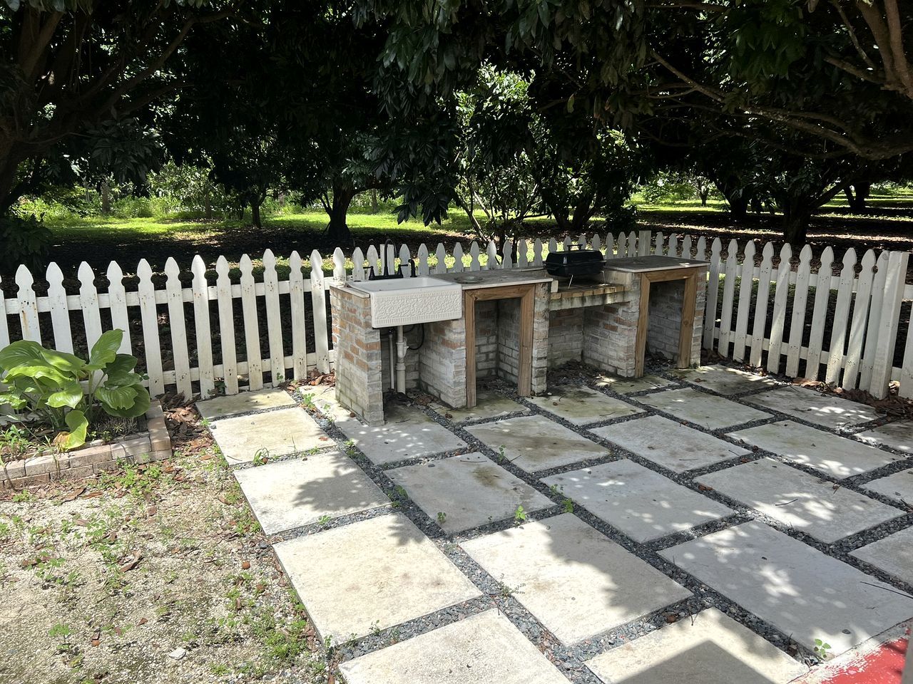 Une terrasse dallée, agrémentée d’une clôture en bois peinte en blanc, de jardinières en pierre et d’une structure en briques.