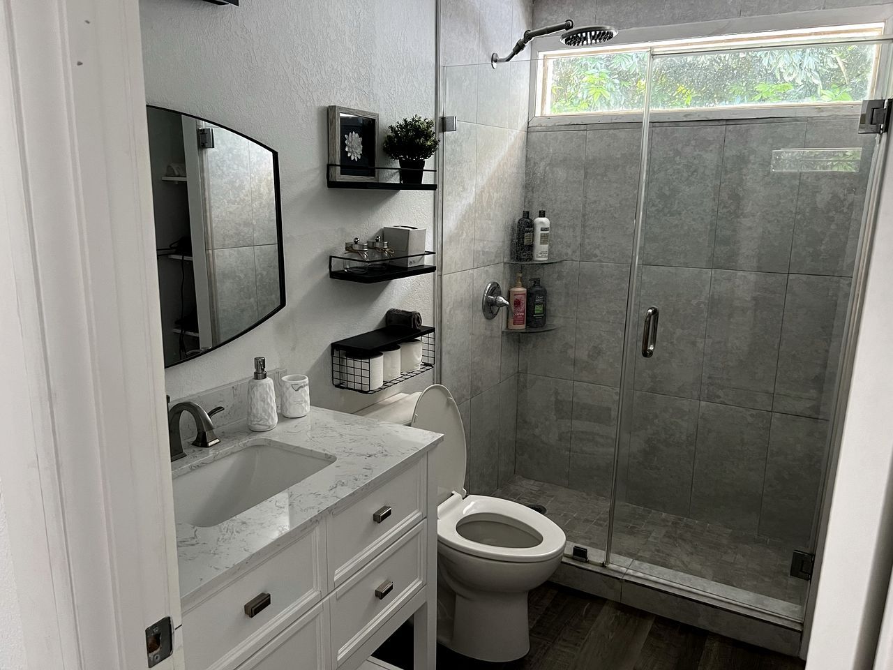Un baño moderno con cabina de ducha de vidrio, inodoro blanco y lavabo de mármol.