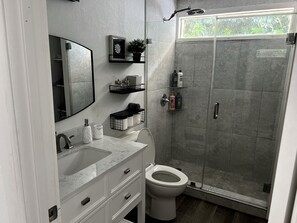 A modern bathroom with a glass shower enclosure, a white toilet, and a marble sink.