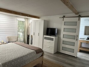A bedroom with a bed, a TV, a wardrobe, and a sliding door.