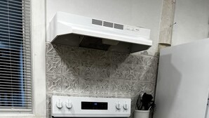 A kitchen with a white stove, oven, and refrigerator, wooden countertops, and patterned backsplash.