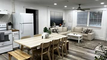 A modern kitchen with a dining area, a sofa, and a ceiling fan.
