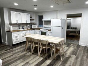 Una cocina moderna con armarios blancos, una mesa de comedor de madera y un refrigerador.