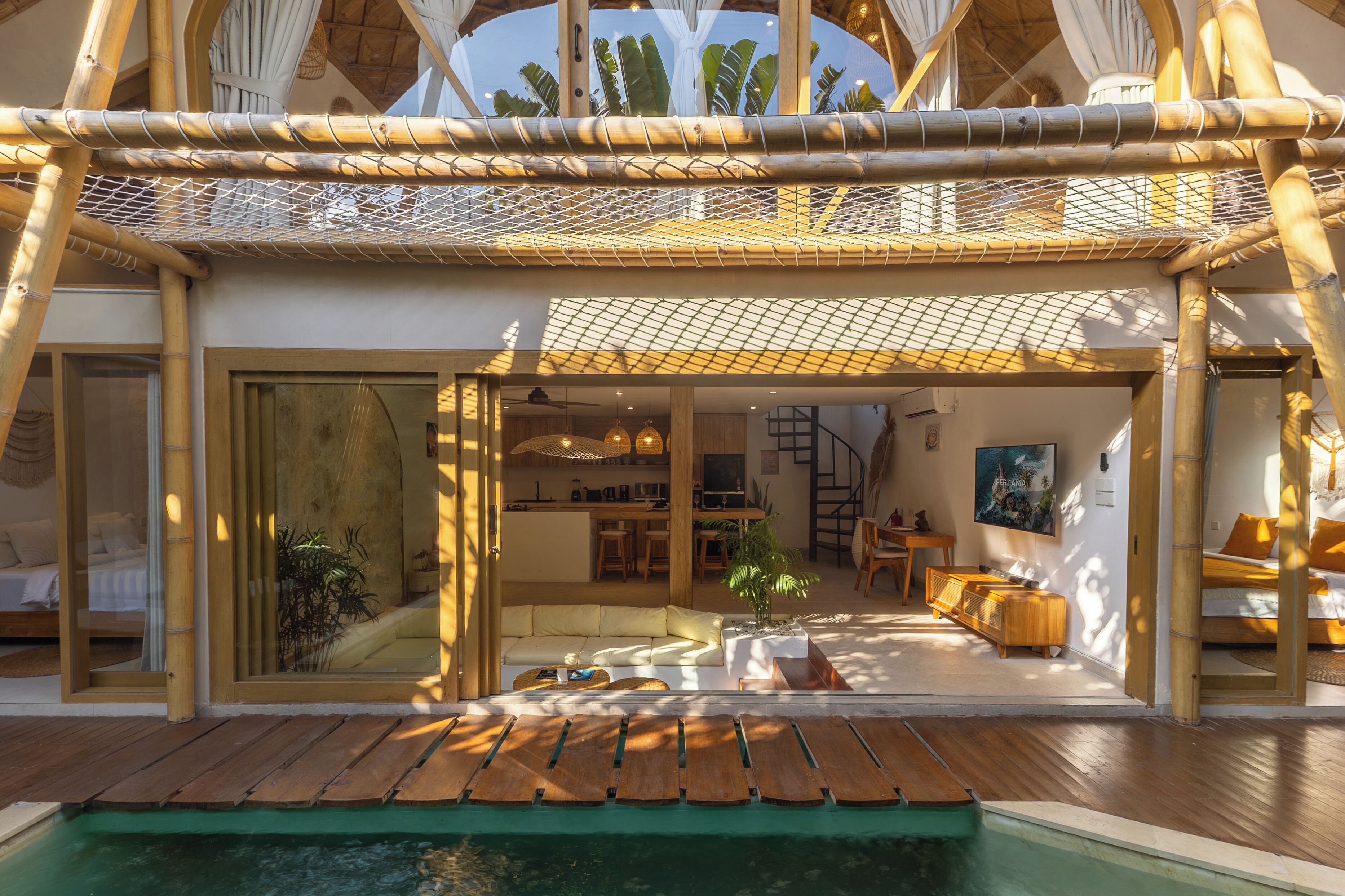 A modern, open-plan living area with a pool, bamboo structures, and a dining area.