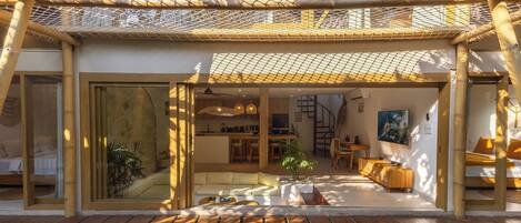 A modern, open-plan living area with a pool, bamboo structures, and a dining area.