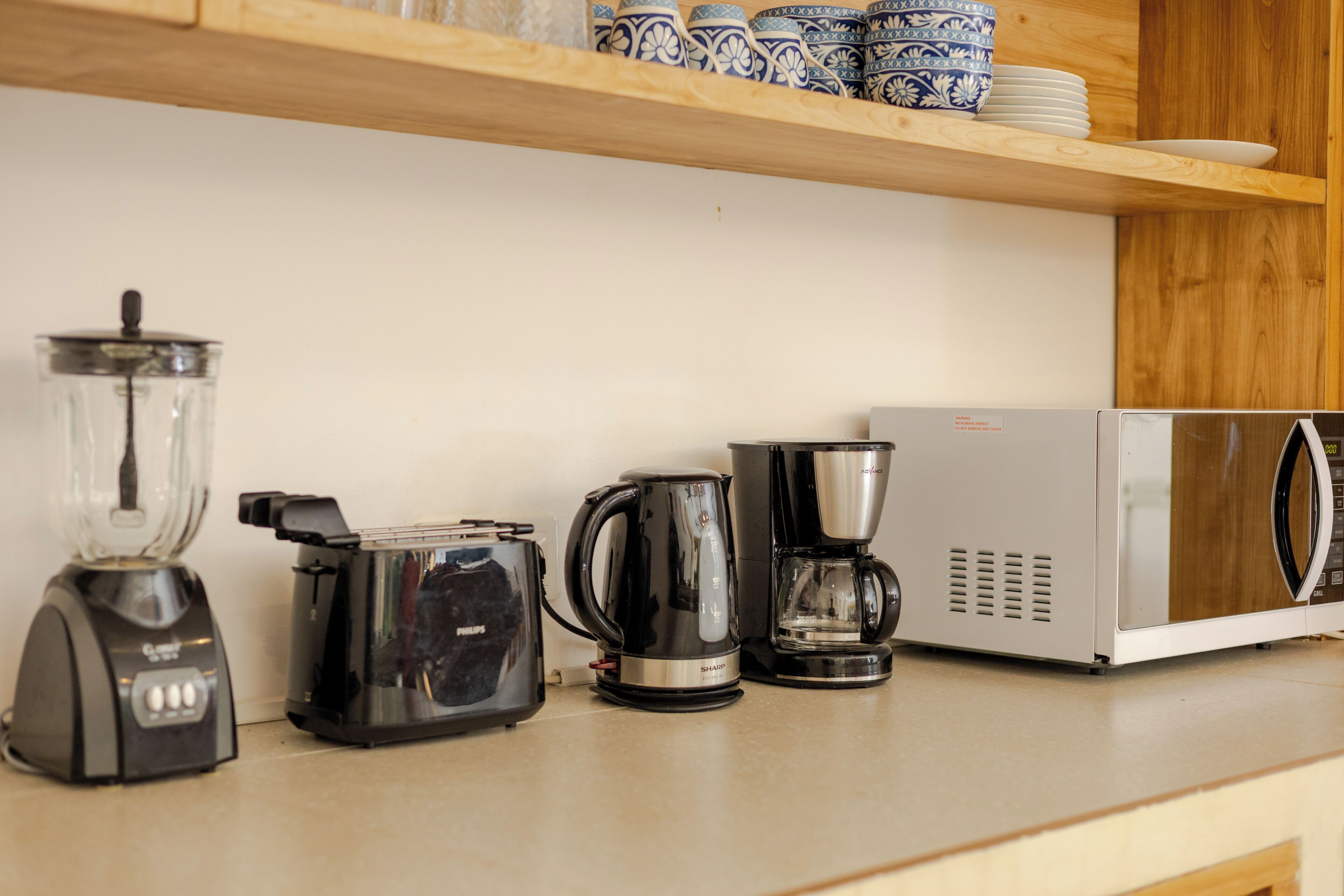 A kitchen counter with a blender, toaster, coffee maker, and microwave.