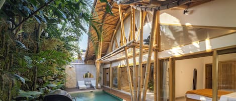 Un área de piscina con terraza de madera, un jacuzzi y una zona de estar cubierta con vistas a la piscina.