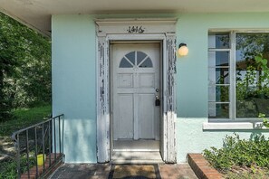 A house with a white door, a small porch, and a window with a light fixture.