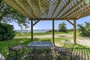 A wooden pergola with a table and chairs, overlooking a body of water. - Pet-Friendly Waterfront Cottage on the Chesapeake Bay, Virginia (Norfolk)