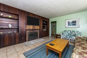 A living room with a fireplace, wooden shelves, a television, a sofa, and a coffee table.
