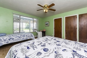 A bedroom with two beds, a ceiling fan, a window with blinds, and a door. - Pet-Friendly Waterfront Cottage on the Chesapeake Bay, Virginia (Norfolk)