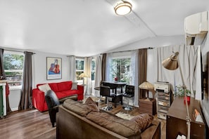 A living room with a red sofa, a brown sofa, a dining table with chairs, a lamp, and a TV.