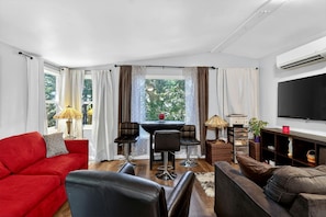 A living room with a red sofa, black chairs, a coffee table, and a TV.