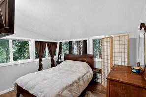 A bedroom with a bed, a nightstand, a wooden dresser, a shoji screen, and a window with curtains.