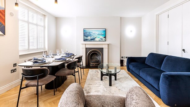 A modern living room with a dining area, a fireplace, and a blue sofa. - Elegant Marylebone/baker St Escape (London)