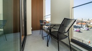A balcony with a table and chairs, a view of the street, and a wooden slatted wall. - New central studio with balcony (Limassol)