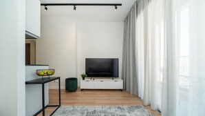 A modern living room with a flat-screen TV, a minimalist console table, and a patterned rug. - New central studio with balcony (Limassol)