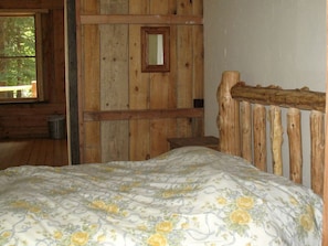 Une chambre dans une cabane en bois, avec un lit, une fenêtre et une porte.