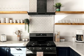 A modern kitchen with a gas stove, a coffee maker, and a toaster. - Dreamy Vacation Rental with Fire Pit and Fantastic Desert Views in Yucca Valley, California (Yucca Valley)