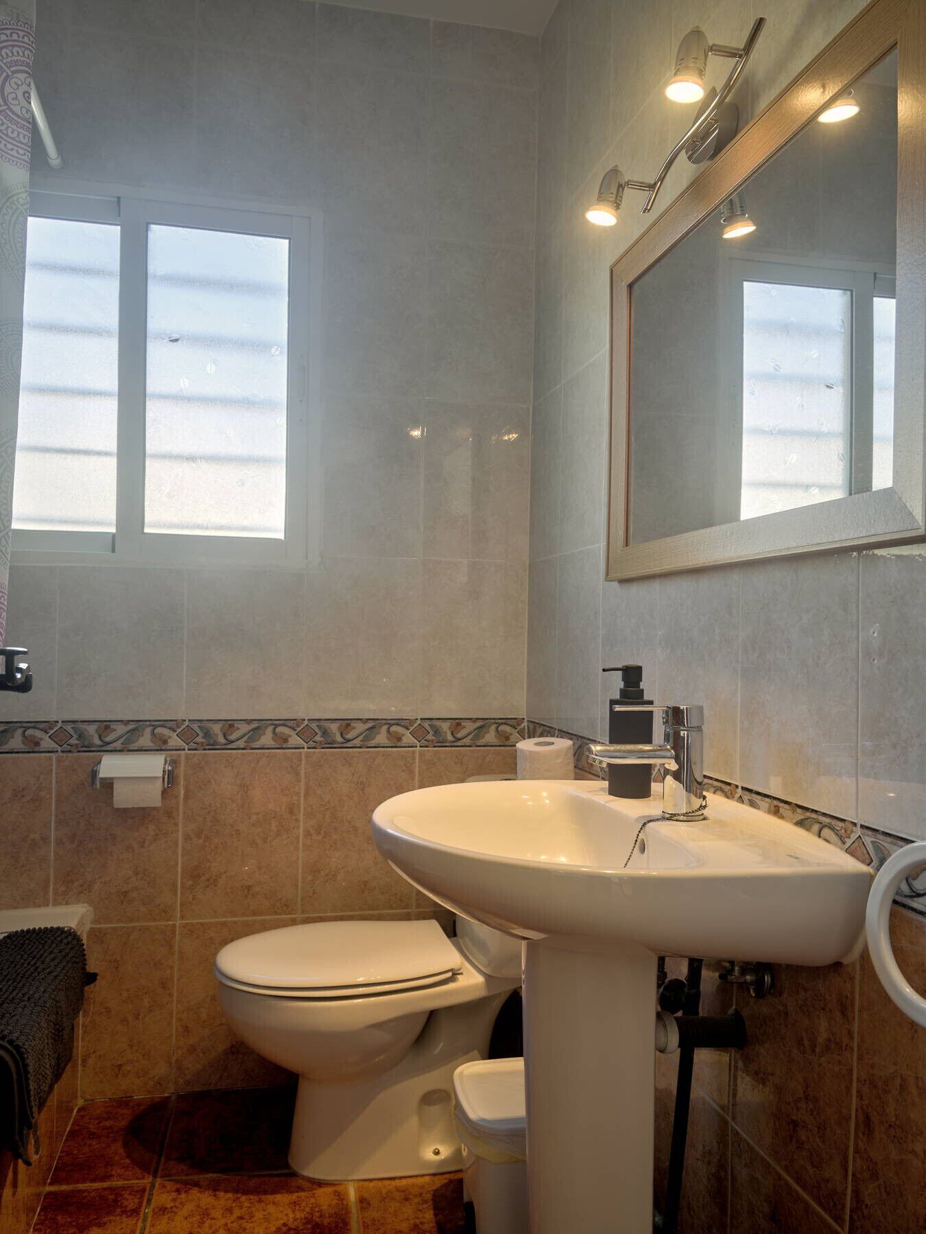 A bathroom with a toilet, sink, and mirror.