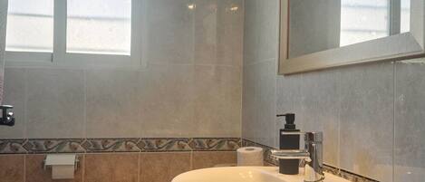 A bathroom with a toilet, sink, and mirror.