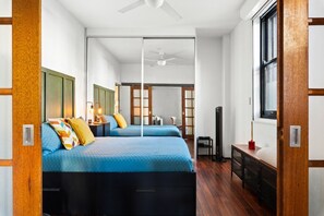 Ett modernt hotellrum med två sängar, en takfläkt, en TV och ett fönster.