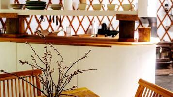 A wooden table with a vase, a wooden bench, and a shelf with glassware.