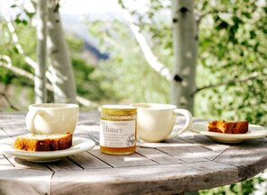 A wooden table with a jar of honey, two white cups, and a slice of cake.