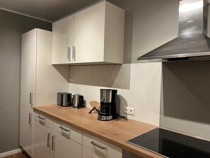 Eine Küche mit weißen Schränken, einer Holzauskładung, einer Kaffeemaschine und einem Herd.