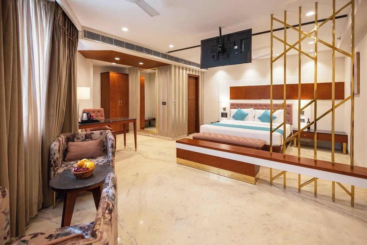 Ein Hotelzimmer mit Bett, Schreibtisch, Stuhl, einem kleinen Tisch mit Früchten und einem Fernseher.